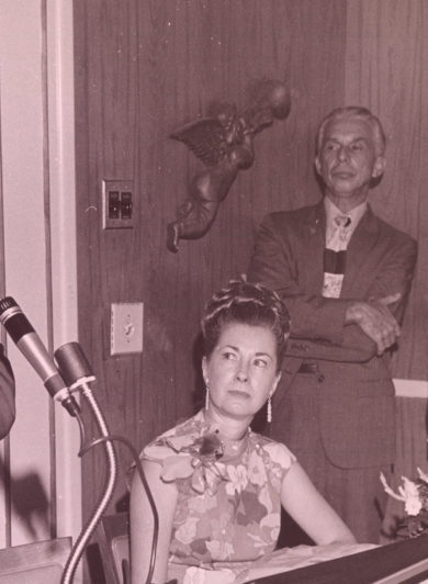 Photo Ancienne d'un homme les bras croisés parlant dans un micro. 2 hommes et une femme le regardent