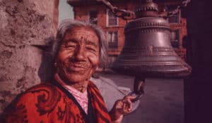 Vielle dame souriant à coté d'une cloche en amérique du sud