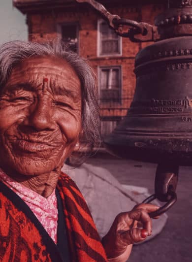 Vielle dame souriant à coté d'une cloche en amérique du sud